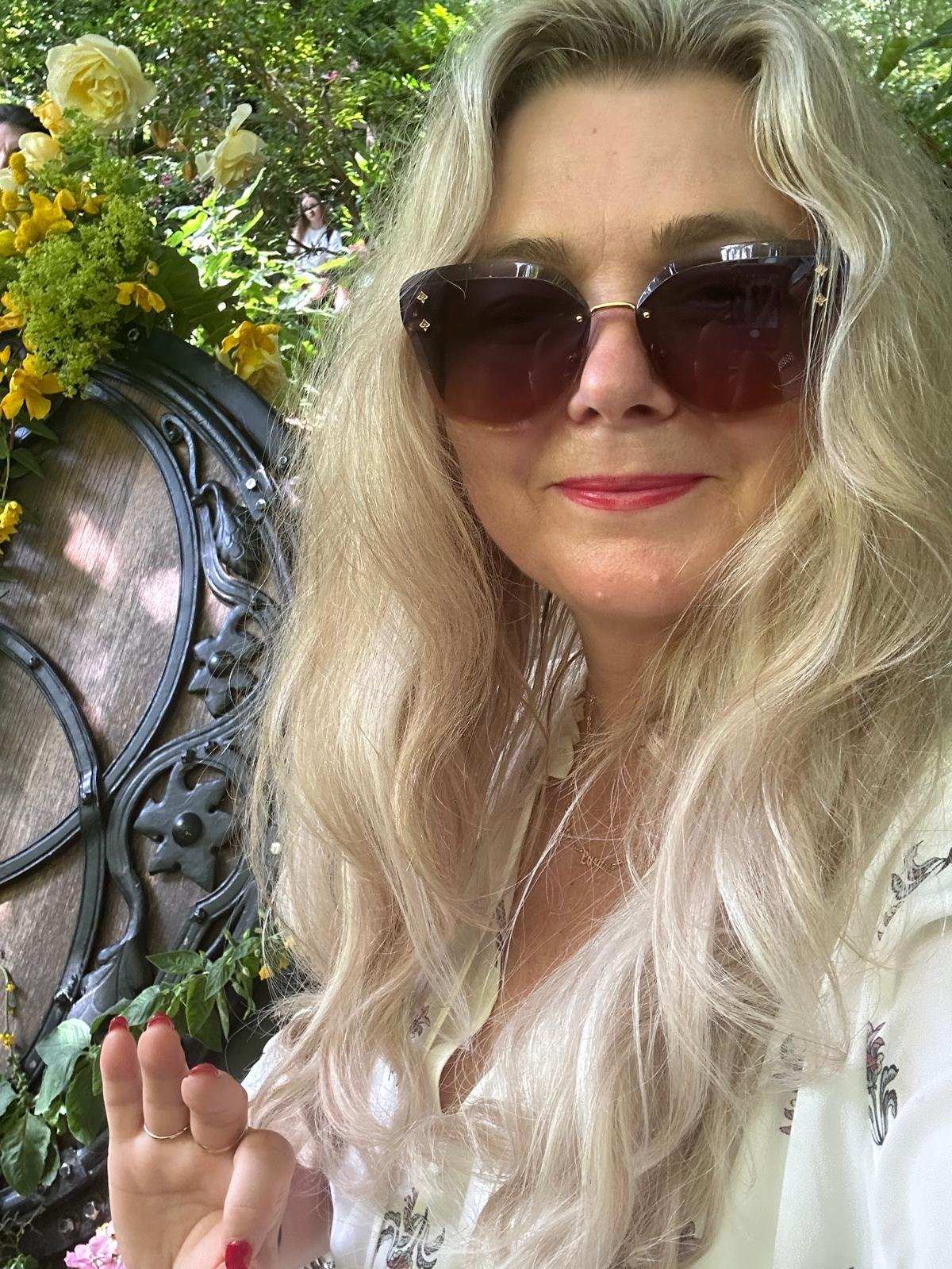 The Galactic High Priestess smiling in a warm sunlit garden