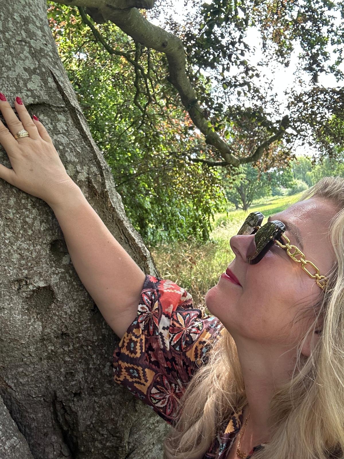 A hand with a gold ring reaching up a tree trunk in golden light
